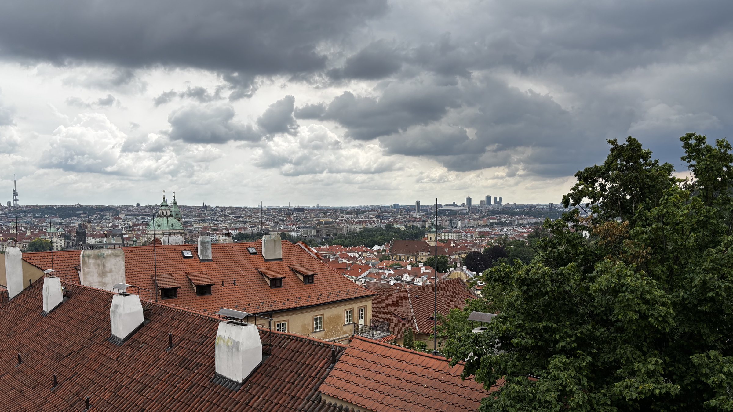 Parapet I, Kostel Panny Marie Vítězné a Pražské Jezulátko. A view across Prague with the domes of the Church of Our Lady Victorious and The Infant Jesus visible above the buildings in the foreground while in the distance is Basilica of Saint Peter & Saint Paul and the Žižkov Television Tower.